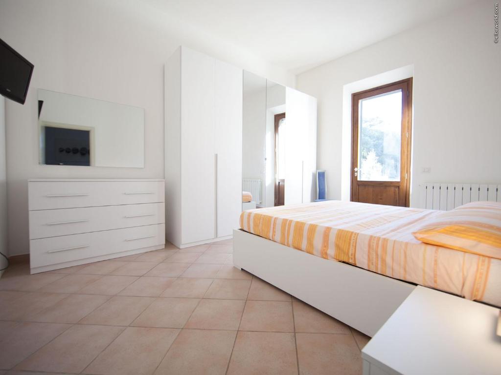una camera bianca con letto e TV di Villa La Pila Bilo a Marina di Campo