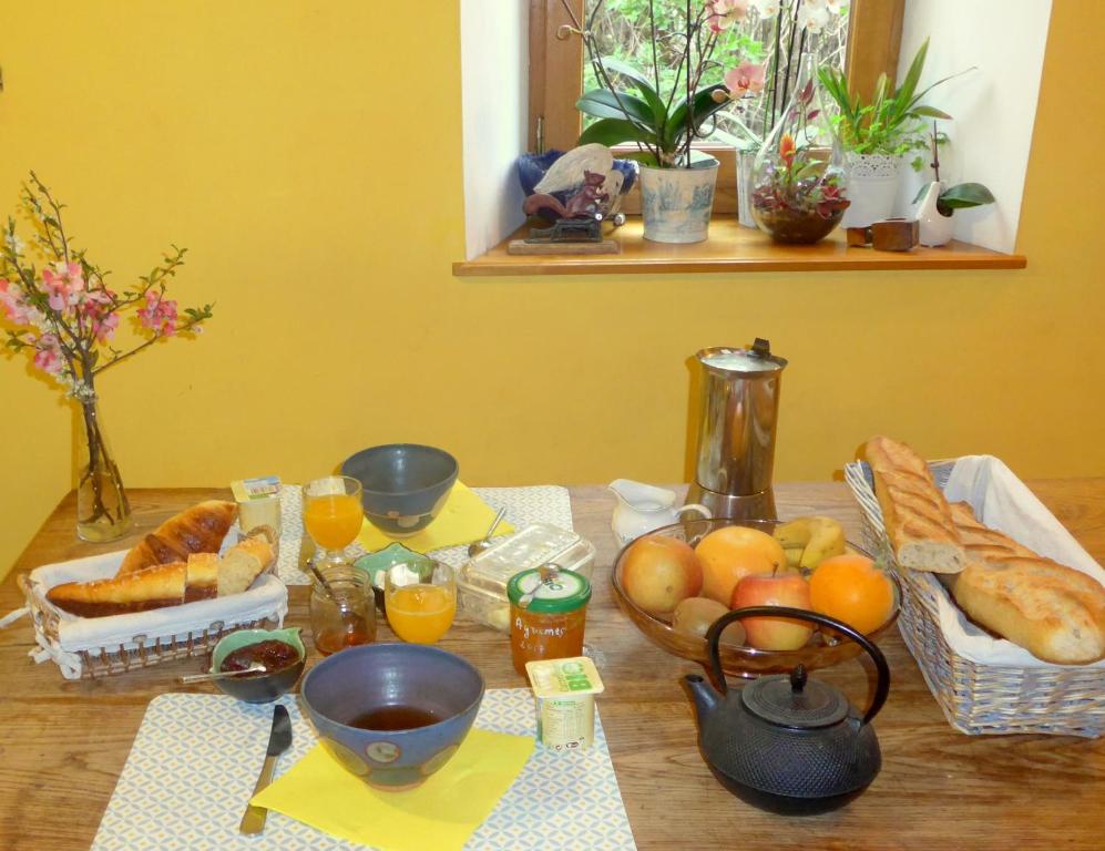 a table with bread and fruit on a table at La Colline Bleue in Banne