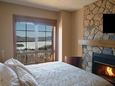 a bedroom with a fireplace and a bed and a window at Luxurious Equinoxe Ski-in/Ski-out in Mont-Tremblant