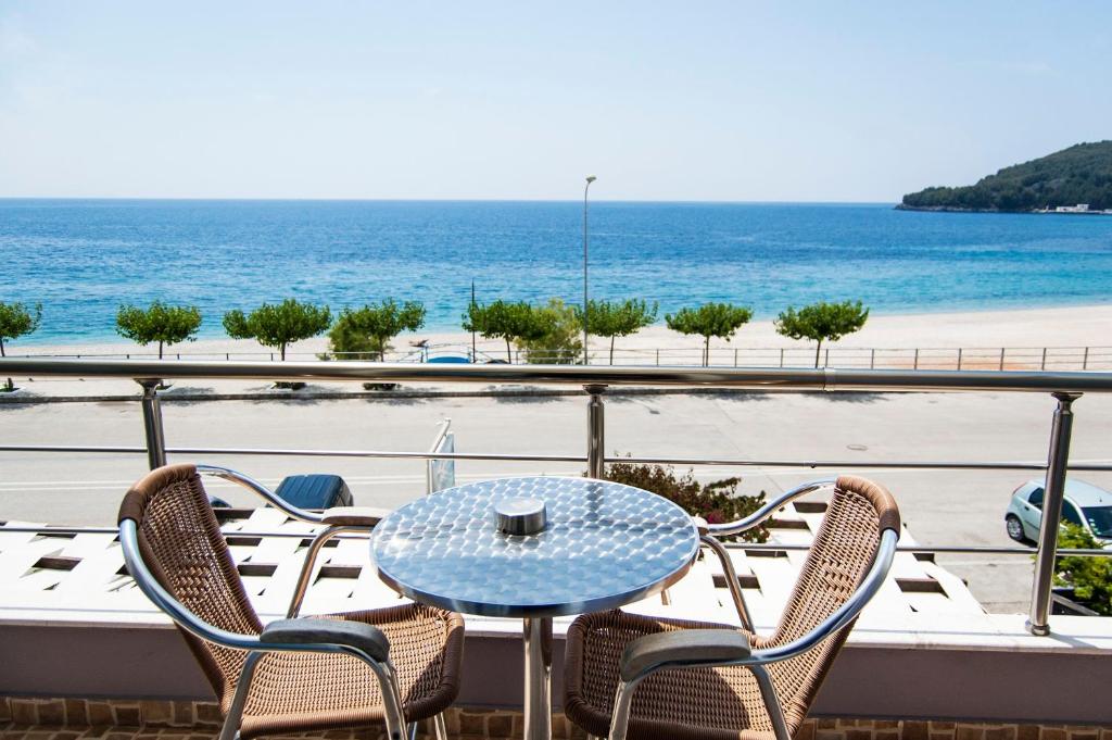 a table and chairs on a balcony with the beach at Dhima Hotel in Himare