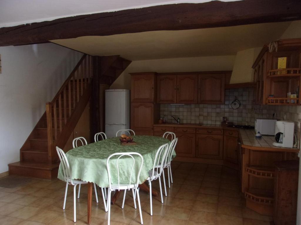 a kitchen with a table with chairs and a refrigerator at Gîte à la campagne in Cressonsacq