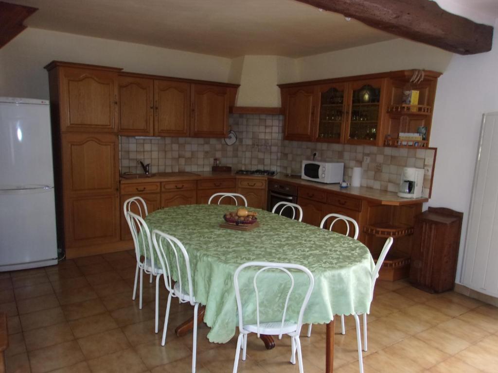 a kitchen with a table with chairs and a refrigerator at Gîte à la campagne in Cressonsacq