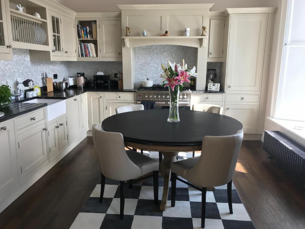 uma cozinha com uma mesa com cadeiras e um vaso de flores em Stramongate Apartment em Kendal