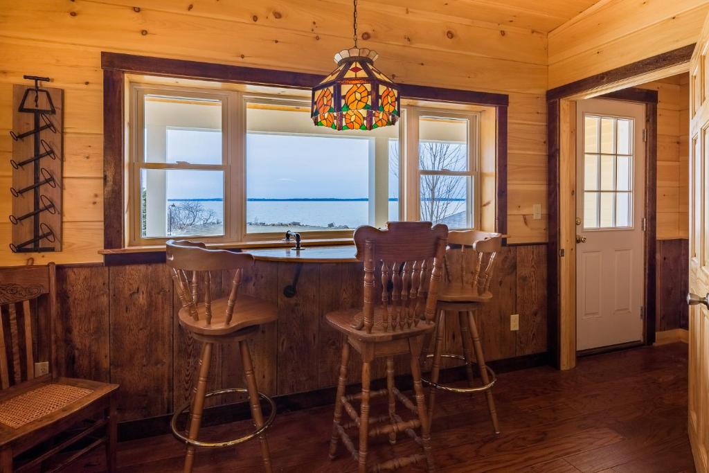 a kitchen with a bar with chairs and windows at Beach Cottage Inn in Lincolnville