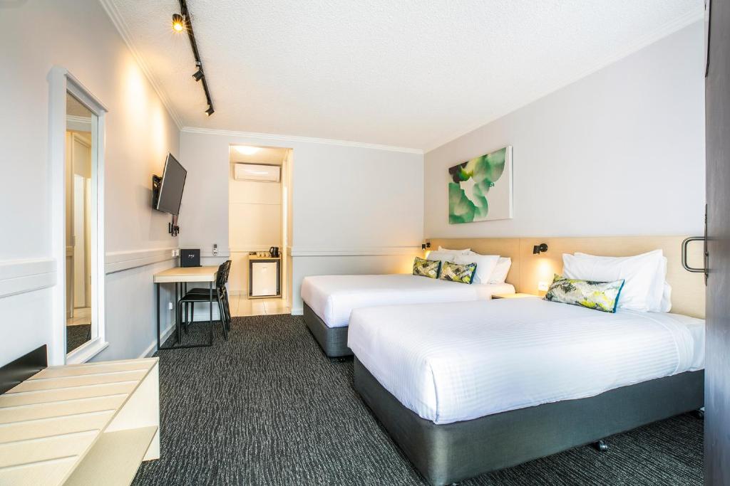 a hotel room with two beds and a desk at Nightcap at Matthew Flinders Hotel in Chadstone