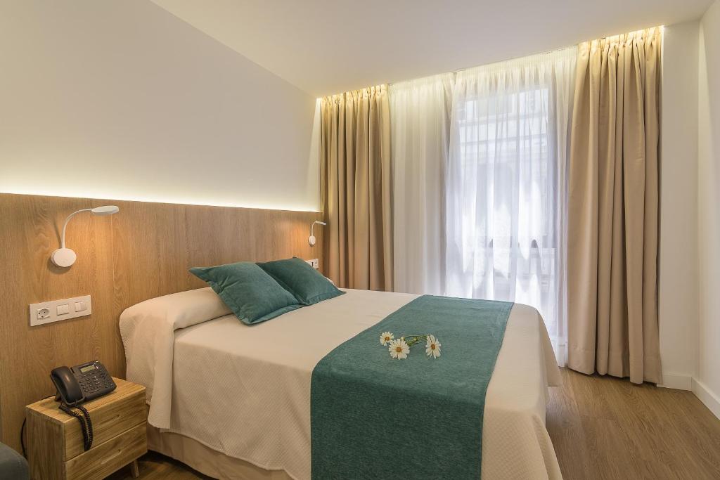 1 dormitorio con 1 cama con manta verde y ventana en Lofts MSH Canarias en Las Palmas de Gran Canaria