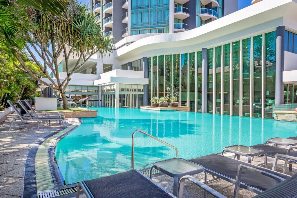 une grande piscine avec des chaises et un bâtiment dans l'établissement Mantra Legends Hotel, à Gold Coast