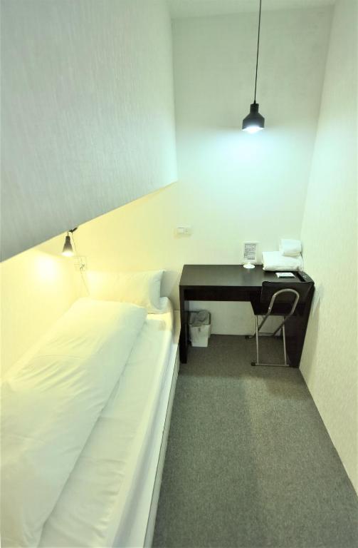 a bed in a room with a desk and a bed sidx sidx sidx at Inn Cube - Taipei Main Station in Taipei