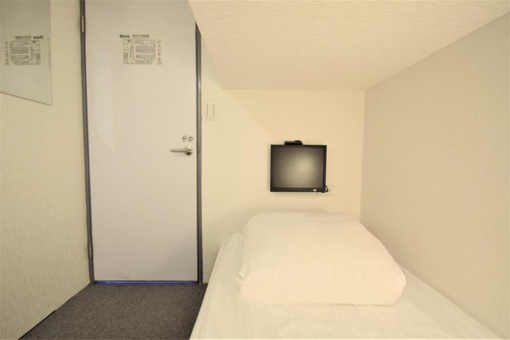 台北市にあるイン キューブ タイペイ メイン ステーションのベッド1台、壁掛けテレビが備わる小さな客室です。