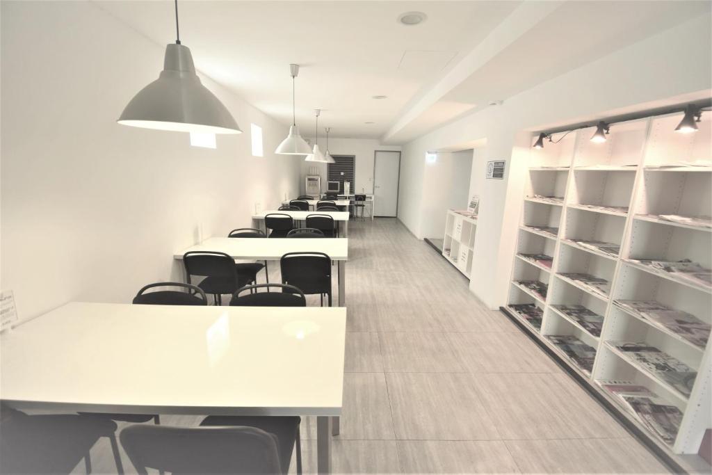 a room with white tables and chairs and shelves at Inn Cube - Taipei Main Station in Taipei