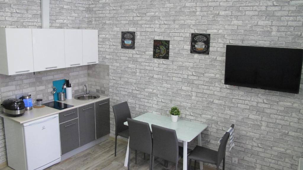 アドレルにあるApartment on Bulvar Nadezhd 6/2のレンガの壁にテレビとテーブル付きのキッチンが備わります。