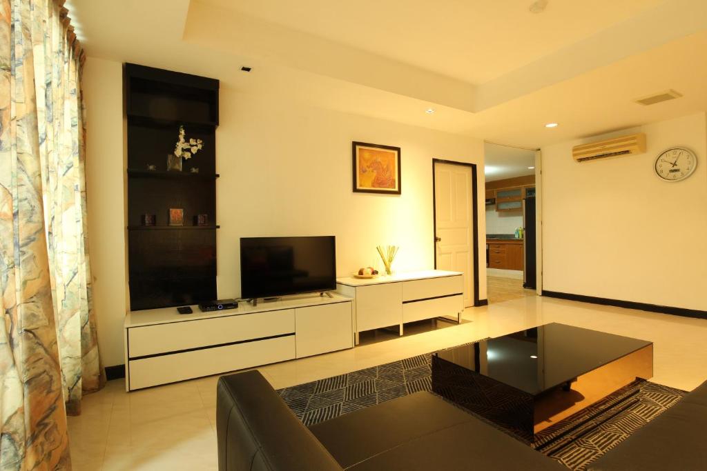 een woonkamer met een televisie en een bank bij Serena Sathorn Suites in Bangkok