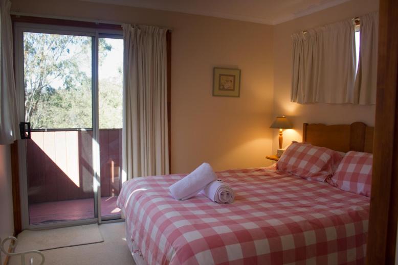 a bedroom with a bed with a red and white checkered blanket at Whiskey Gully Wines in Stanthorpe