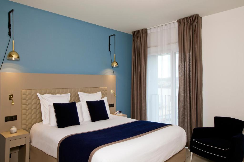 a hotel room with a bed, chair, and nightstand at Residhome Bordeaux in Bordeaux