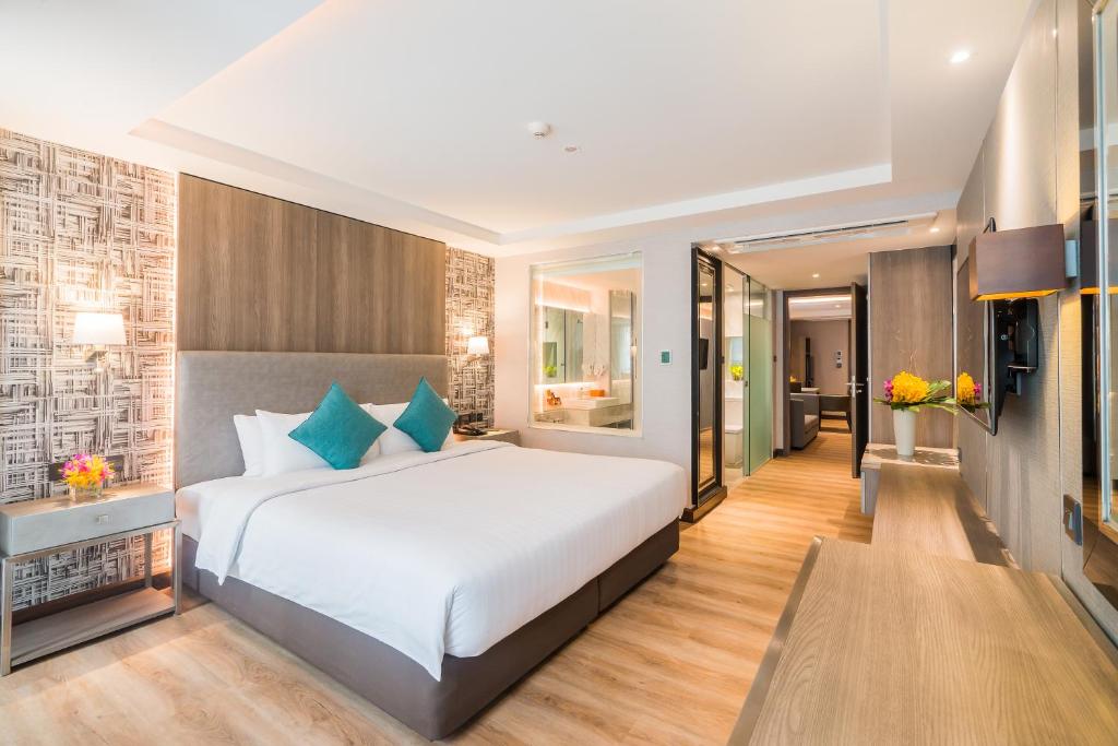 Citrus Suites Sukhumvit 6 by Compass Hospitality في بانكوك: غرفة نوم بسرير كبير ومرآة كبيرة