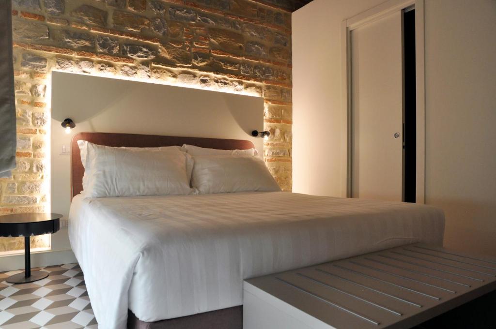 a bedroom with a white bed with a brick wall at Al Foro Annonario in Senigallia