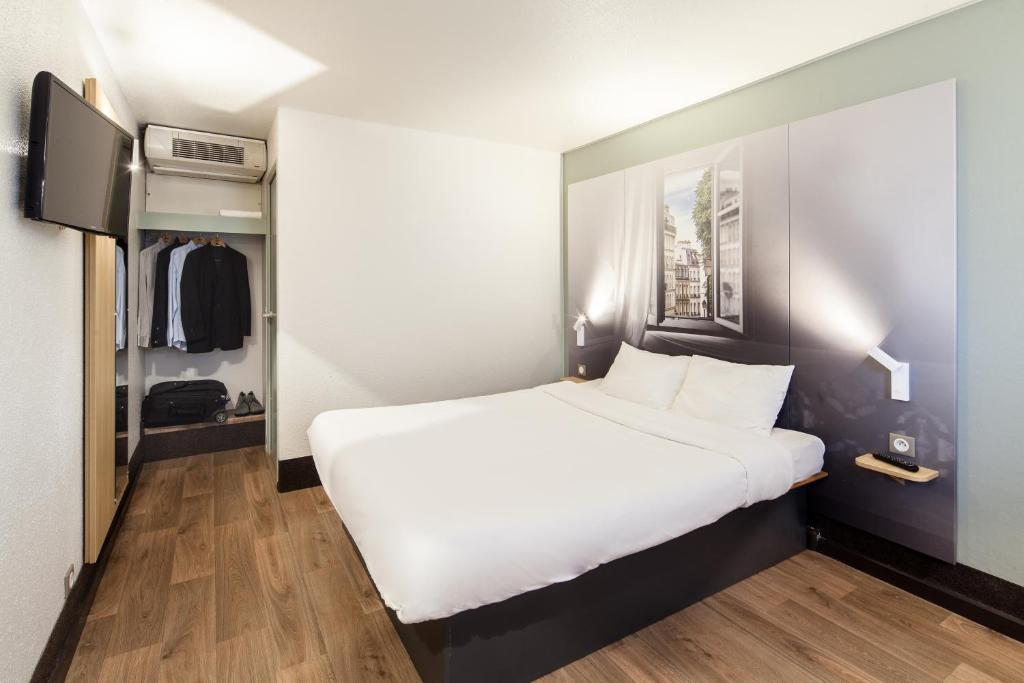 B&B HOTEL La Queue En Brie في La Queue-en-Brie: غرفة نوم بسرير ابيض كبير وتلفزيون