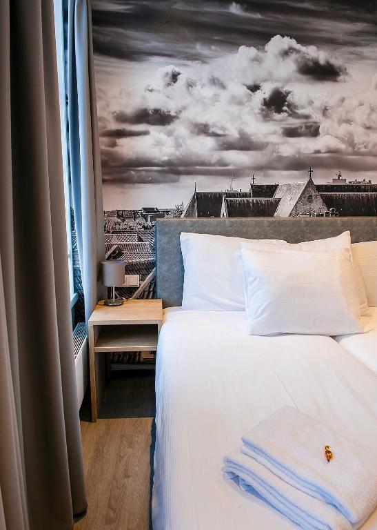 a bedroom with a bed with a view of a city at City2Beach Hotel in Vlissingen