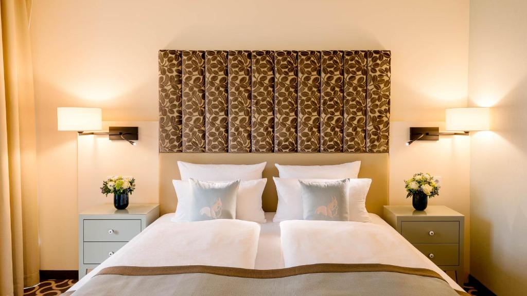 a bedroom with a large white bed with two lamps at Parkhotel Rothof in Munich