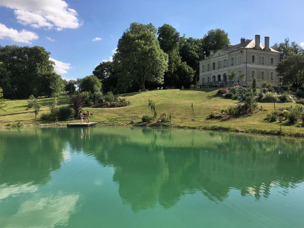 une maison assise au sommet d'une colline à côté d'un lac dans l'établissement B&B Château de Preuil, à Vallenay