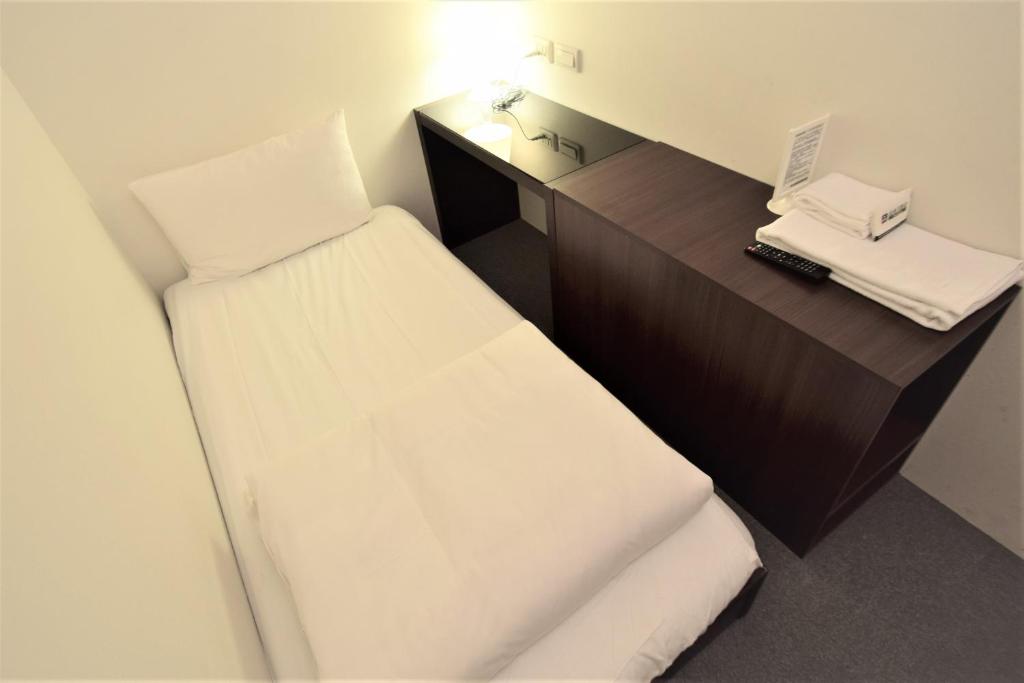 a small room with a bed and a desk with a laptop at Inn Cube - Ximen in Taipei