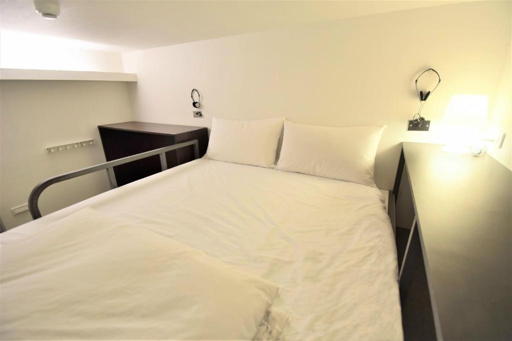 a bed with white sheets and pillows in a room at Inn Cube - Ximen in Taipei