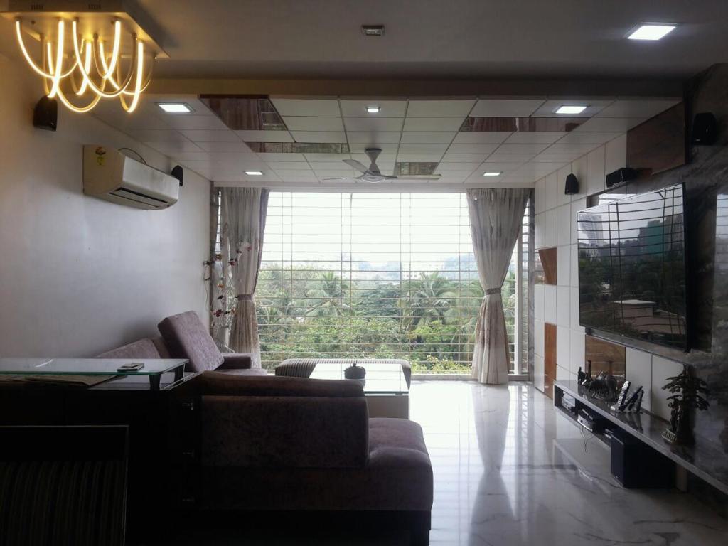 a living room with a couch and a large window at Pinaki Comfort Stay in Mumbai
