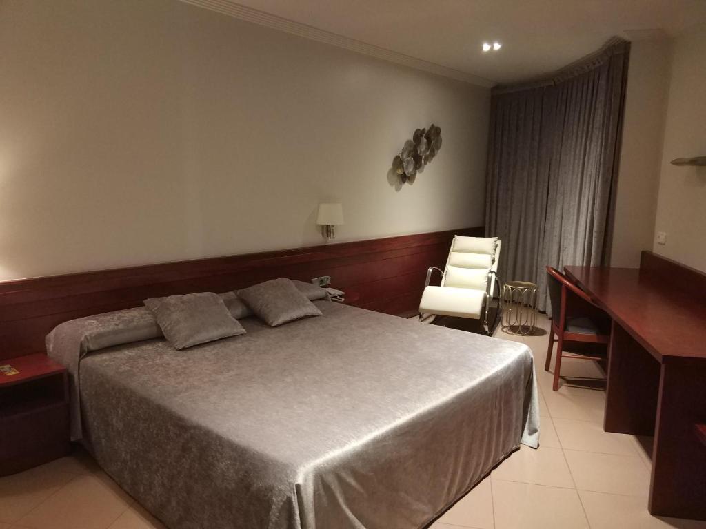 1 dormitorio con cama, escritorio y silla en Hotel Els Noguers, en Manresa