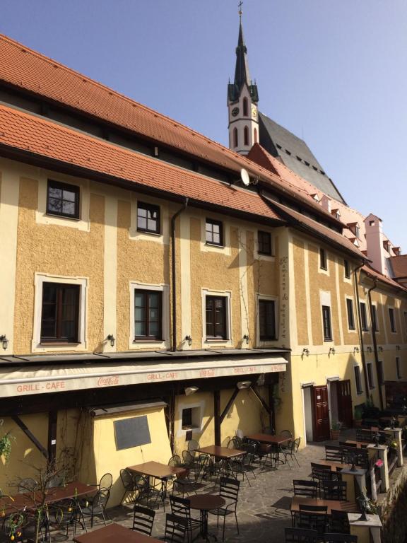 un bâtiment avec des tables et des chaises et une tour d'horloge dans l'établissement Pension U Mrázků, à Český Krumlov