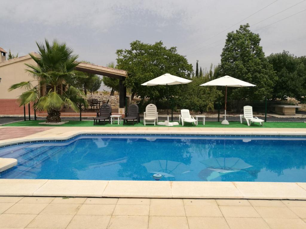una piscina azul con sillas y sombrillas en Casa de Lozano y Rueda, en Moratalla