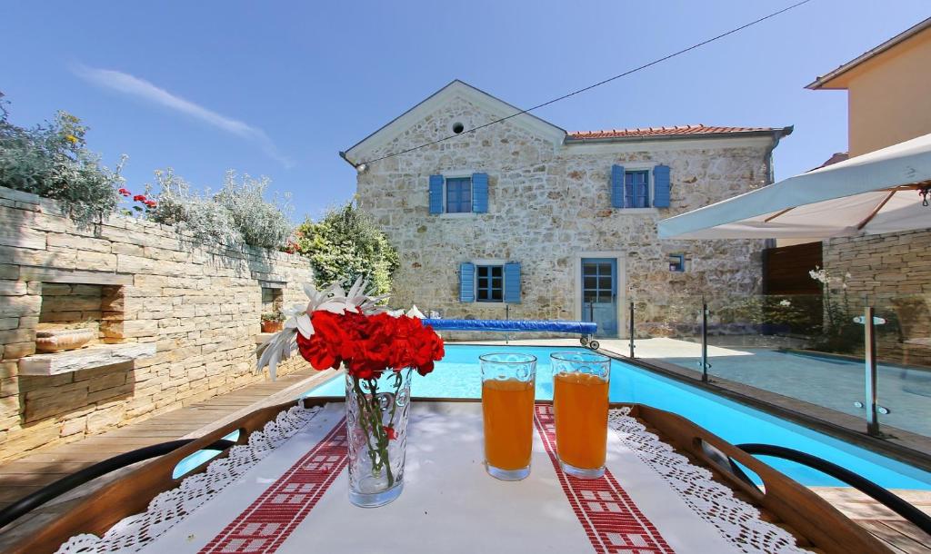 a table with a vase of flowers and two glasses of juice at Olive's Hug in Poljana