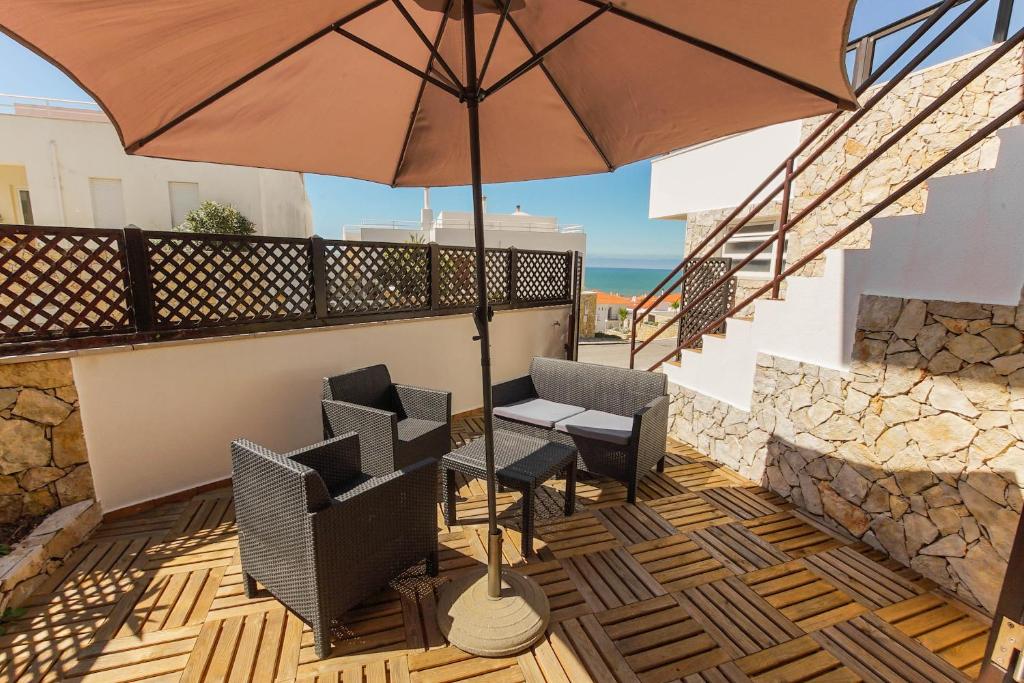 a patio with a table and chairs and an umbrella at Surf Loft Open Space in Ericeira