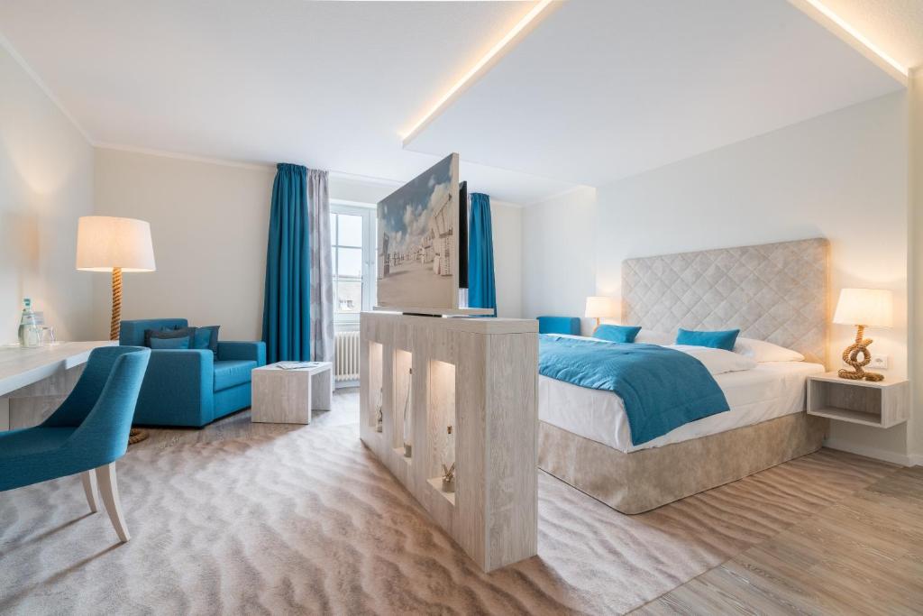 a bedroom with a large bed and a blue chair at Hotel Garni Kölfhamm in Sankt Peter-Ording
