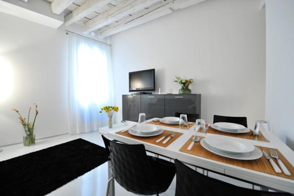 a dining room with a table with chairs and a television at Venetian Apartments in Venice