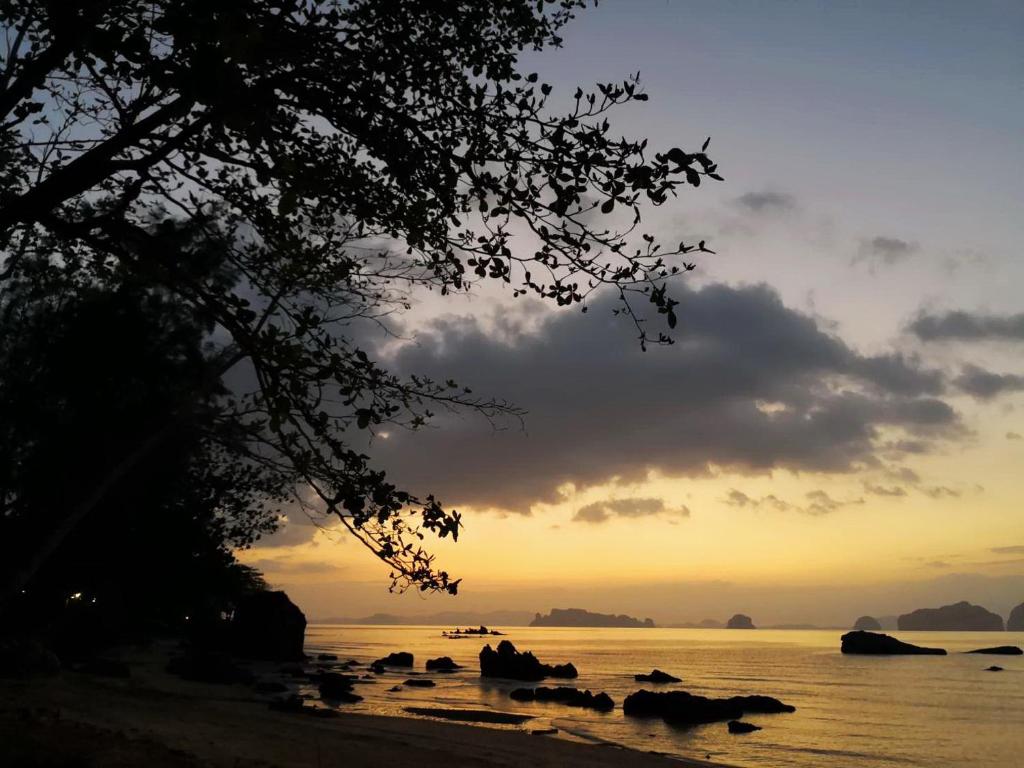 a sunset on the beach with rocks in the water at Krabi Home Resort in Tab Kaek Beach
