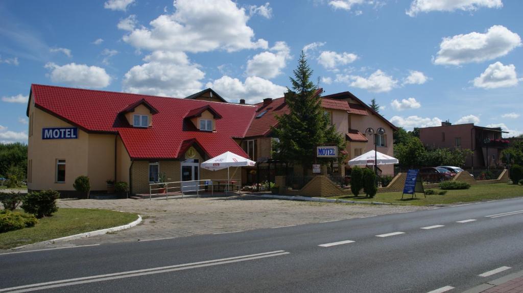 un edificio con techo rojo al lado de una carretera en Motel Za Grosik, en Wałcz