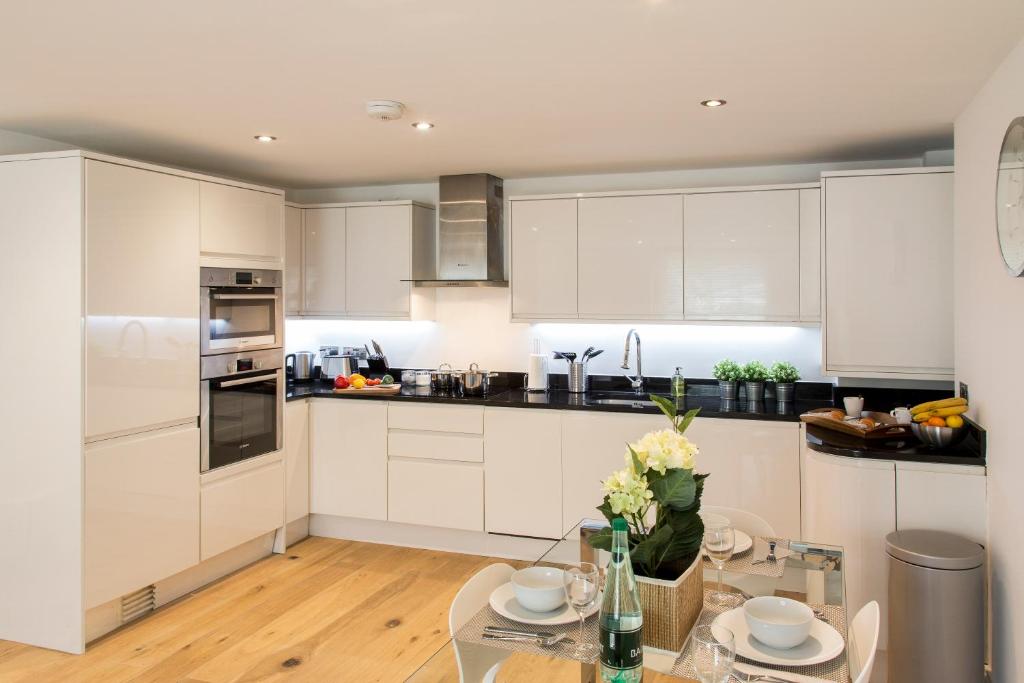 eine Küche mit weißen Schränken und einem Glastisch in der Unterkunft Finchley Central - Luxury 2 bed ground floor apartment in Hendon