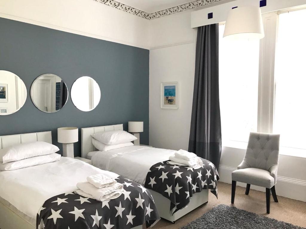 a bedroom with two beds and a chair and mirrors at Bishopton Apartment, near Glasgow in Bishopton