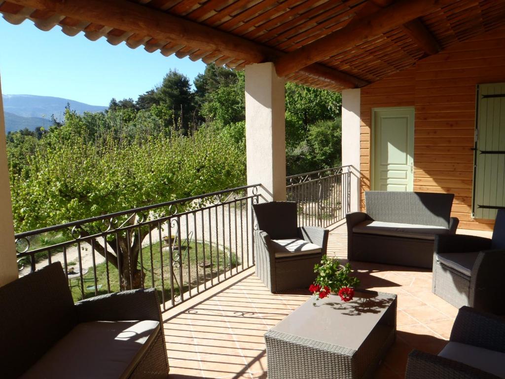 un porche con sillas y una mesa en una terraza en Le Mas des Eglantiers, en Propiac