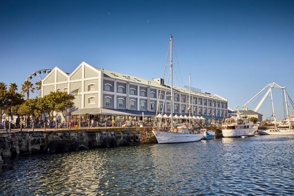 a large building with boats docked in a harbor at Victoria & Alfred Hotel by NEWMARK in Cape Town