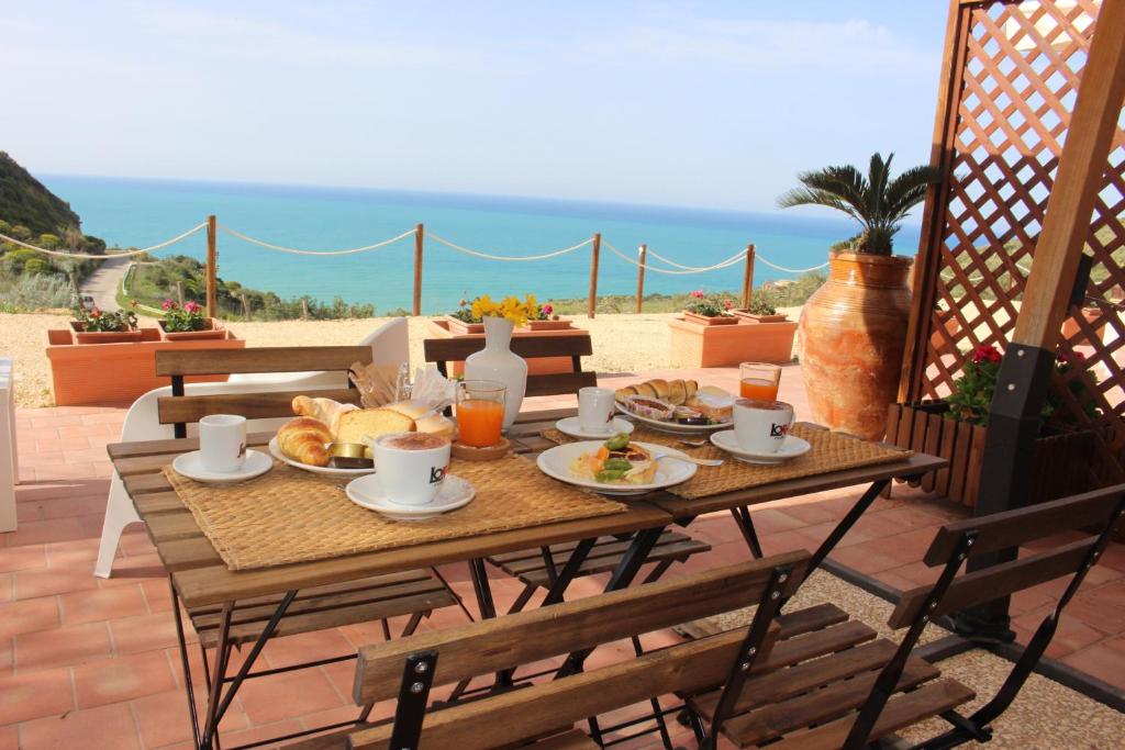 una mesa con comida en un patio con vistas al océano en B&B La Torre en Realmonte