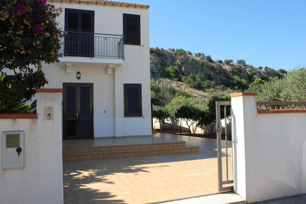 a white house with black doors and a porch at Villa Barraco Paradise in San Vito lo Capo