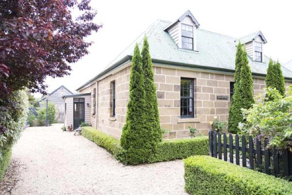 a brick house with trees and a fence at Elm Cottage Barn in Oatlands