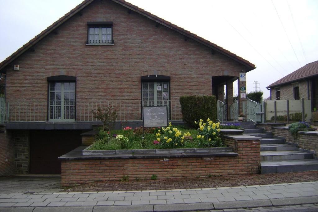 Le Castillon في Trivières: منزل من الطوب مع الزهور أمامه
