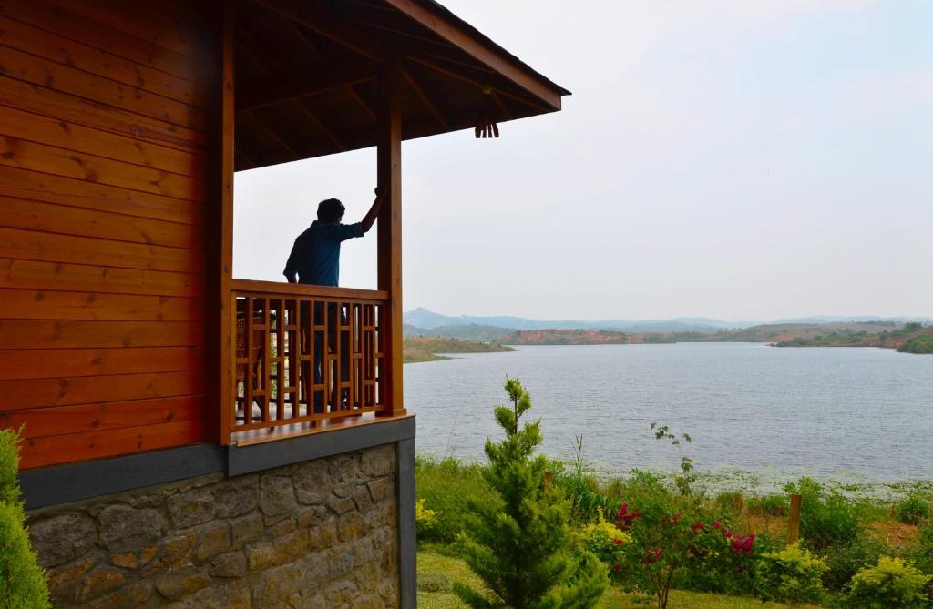 een man op een balkon van een gebouw met uitzicht op het water bij LakeRose Wayanad Resort in Ambalavayal