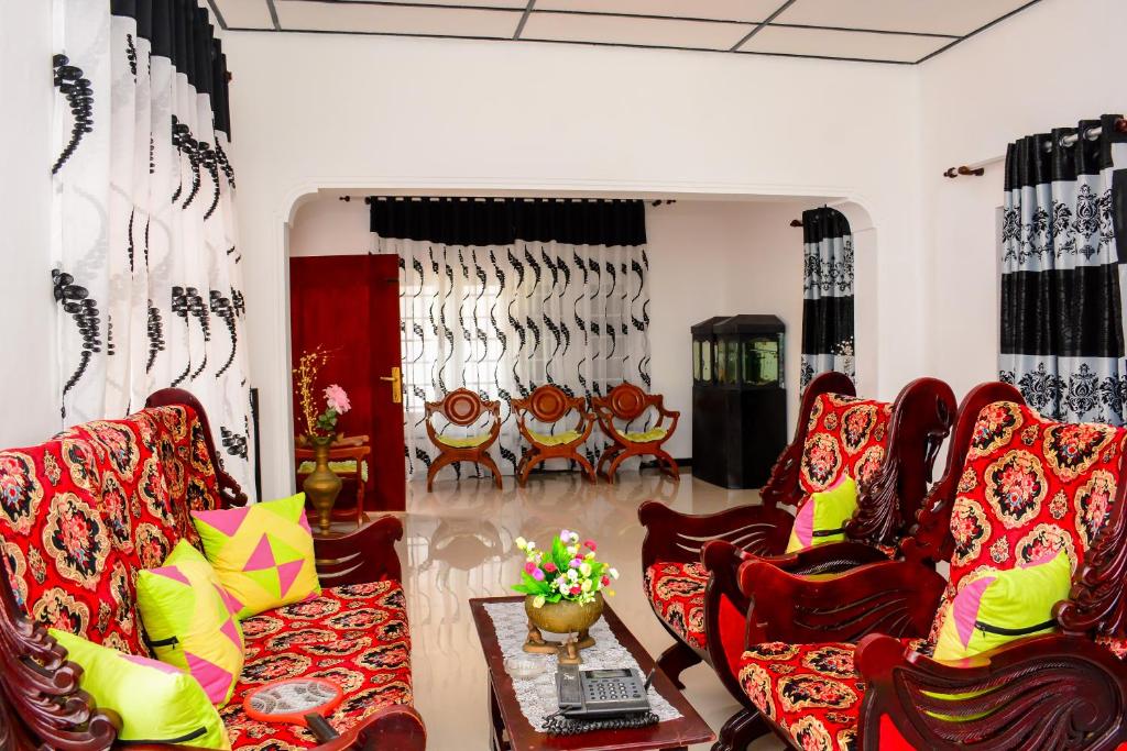 a living room with red chairs and a table at Gloriya Mathews in Negombo