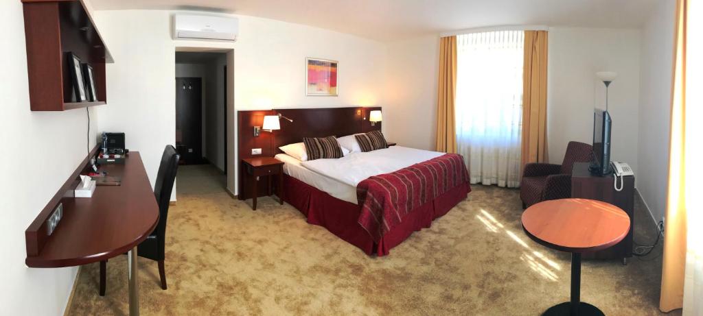 a hotel room with a bed and a chair and a television at Hotel Atrium in Vyškov