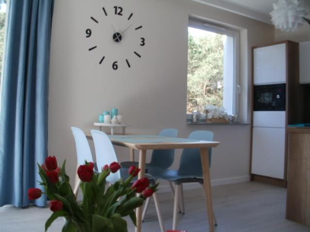 uma cozinha com mesa e cadeiras e um relógio na parede em Apartament nr 19 em Dziwnówek