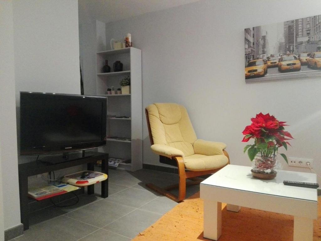 a living room with a television and a chair at COZY APARTAMENT 10 MINUTES FROM THE HEART OF MADRID in Madrid