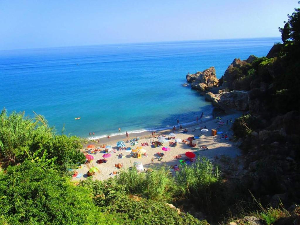 a beach with umbrellas and people on the beach at Rico Apartaments Parador in Nerja